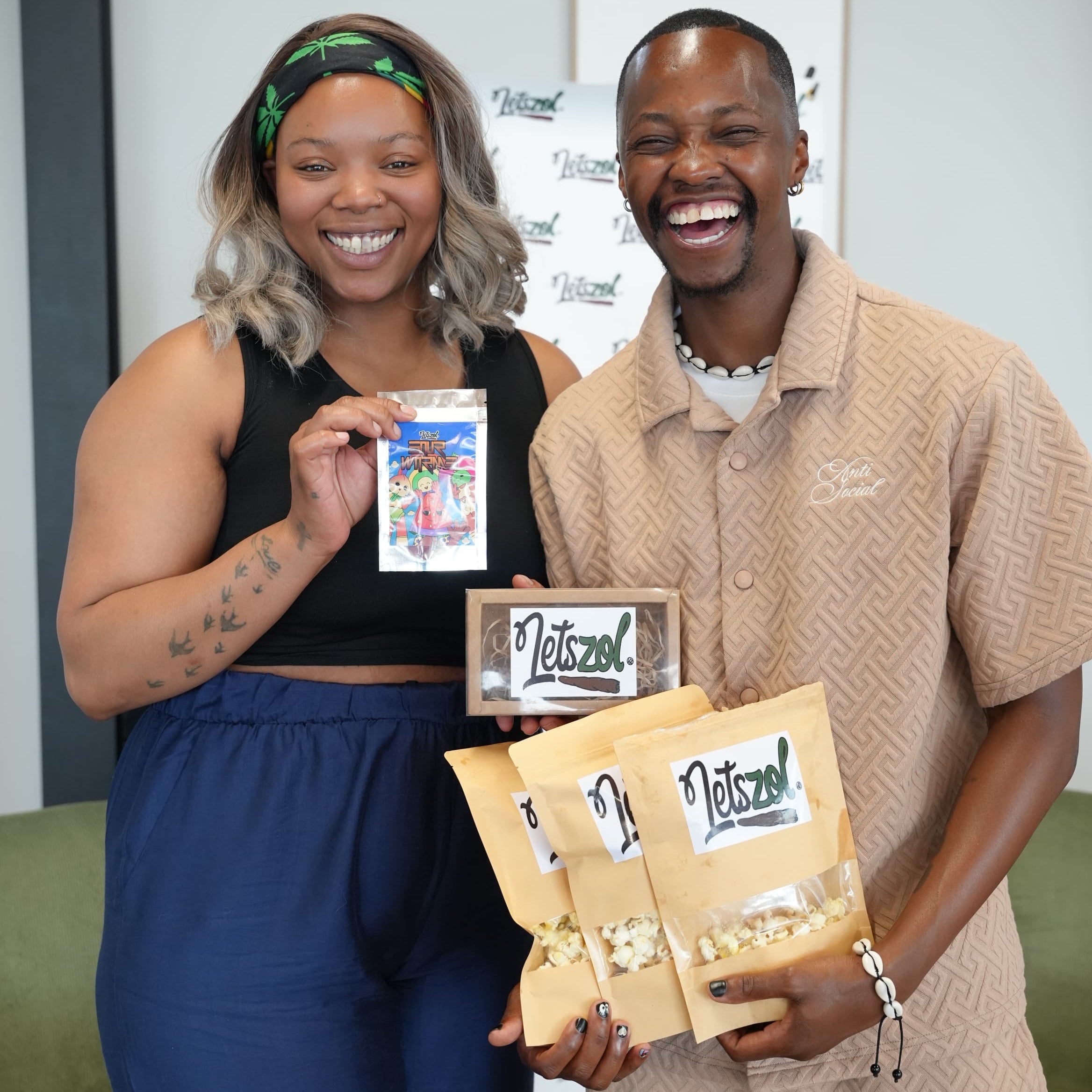 Two people holding packages with a brand logo in an indoor setting
